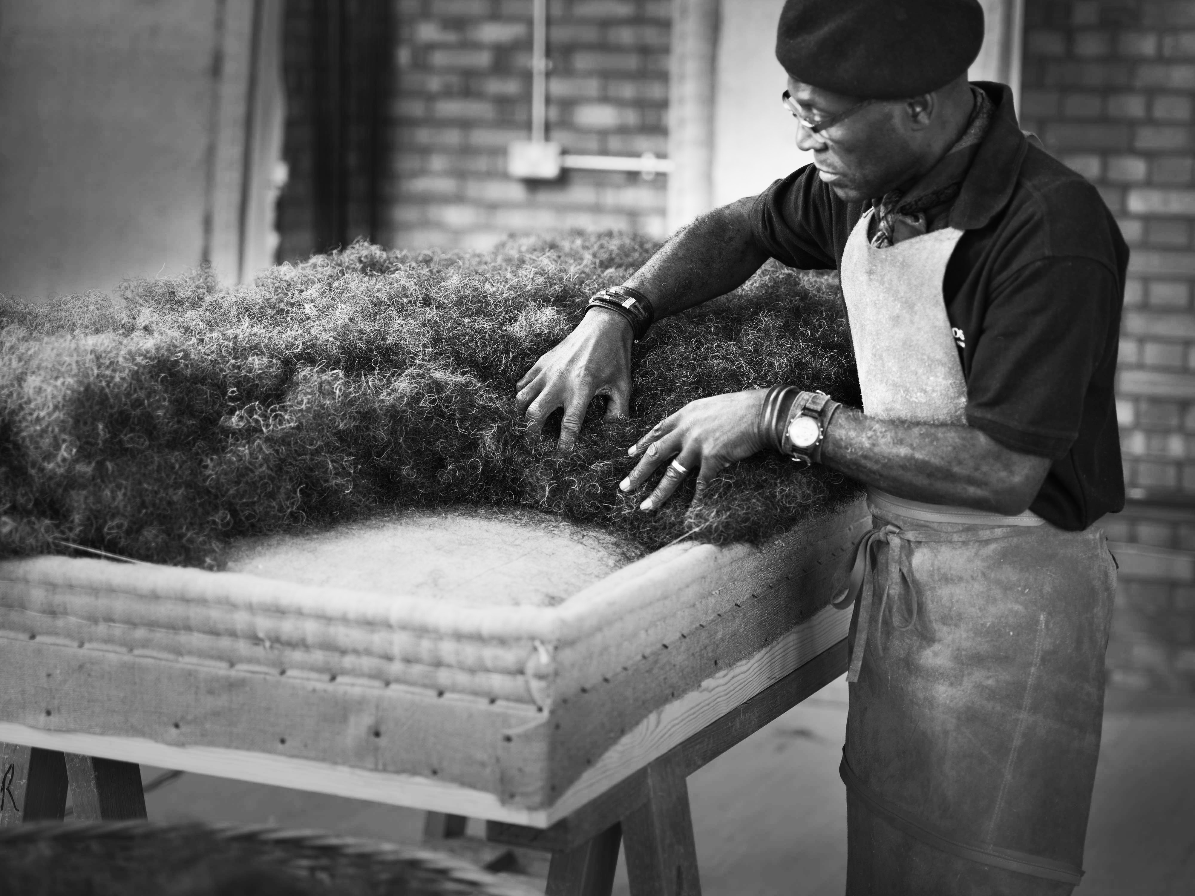 A craftsman adds layers of natural fibres such as wool to the mattress