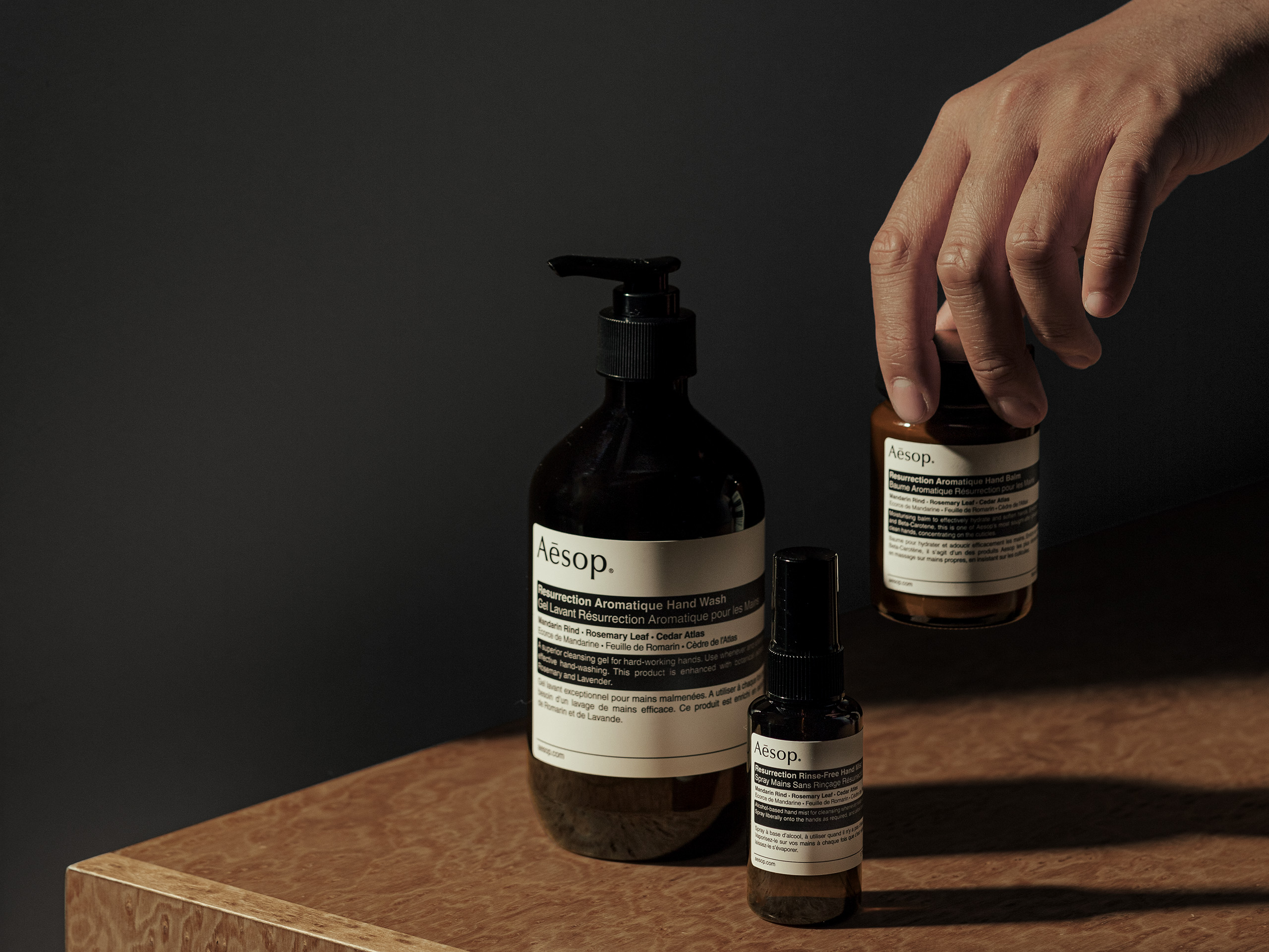 Aesop - hand holding brown bottles 