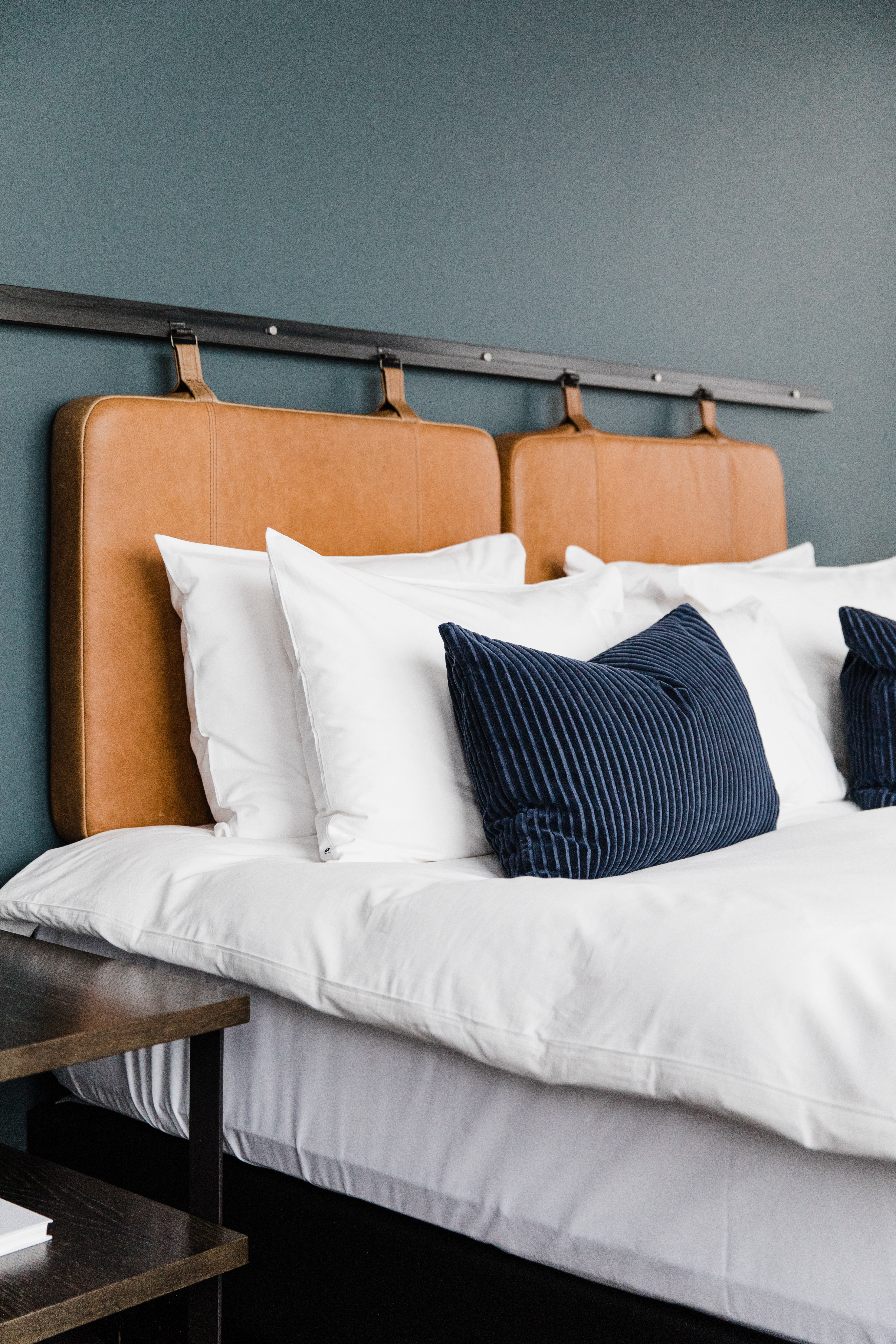 Hotel Exeter - a bed with white sheets, blue cushions and an orange headboard on a grey wall