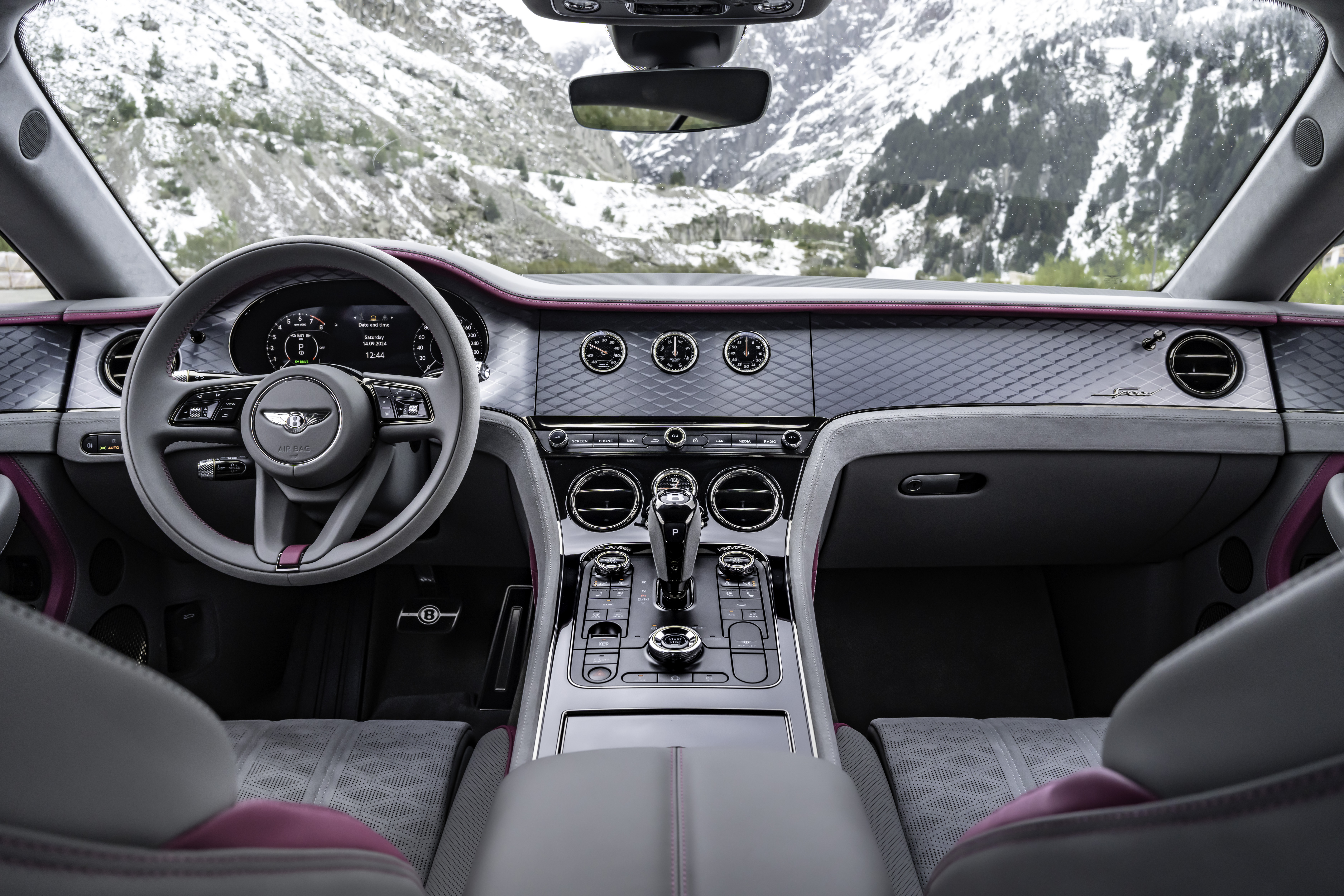 Investment, Tech & Motoring trends 2025 - The interior of a luxury car, highlighting the detailed dashboard with premium materials, analog dials, and a scenic snowy mountain view through the windshield