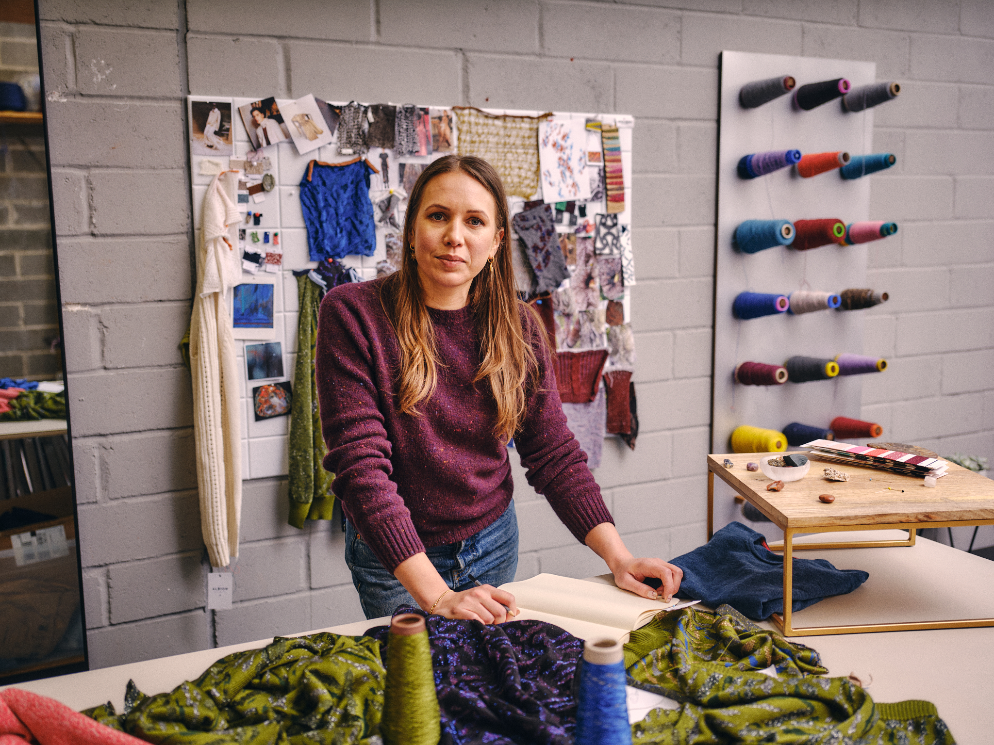 Walpole Brands of Tomorrow 2025 - Genevieve Sweeney handling fabrics, spools of yarn on the wall