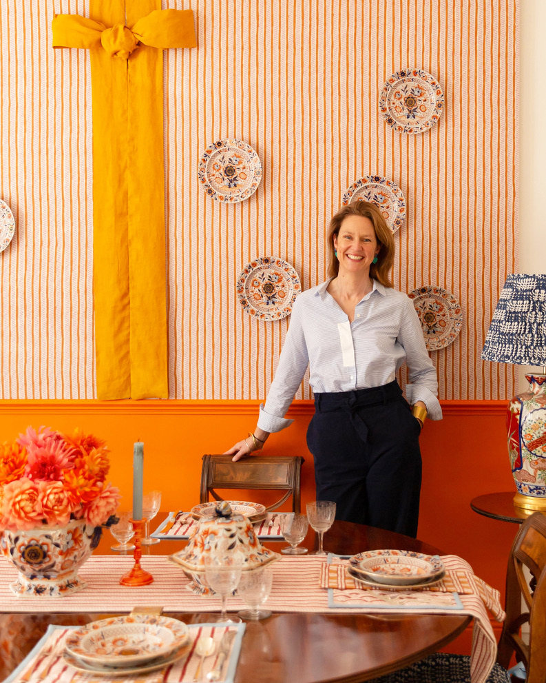 Walpole Brands of Tomorrow 2025 - Molly Mahon stood behind a tablescape, with a striped orange wall and plates behind her