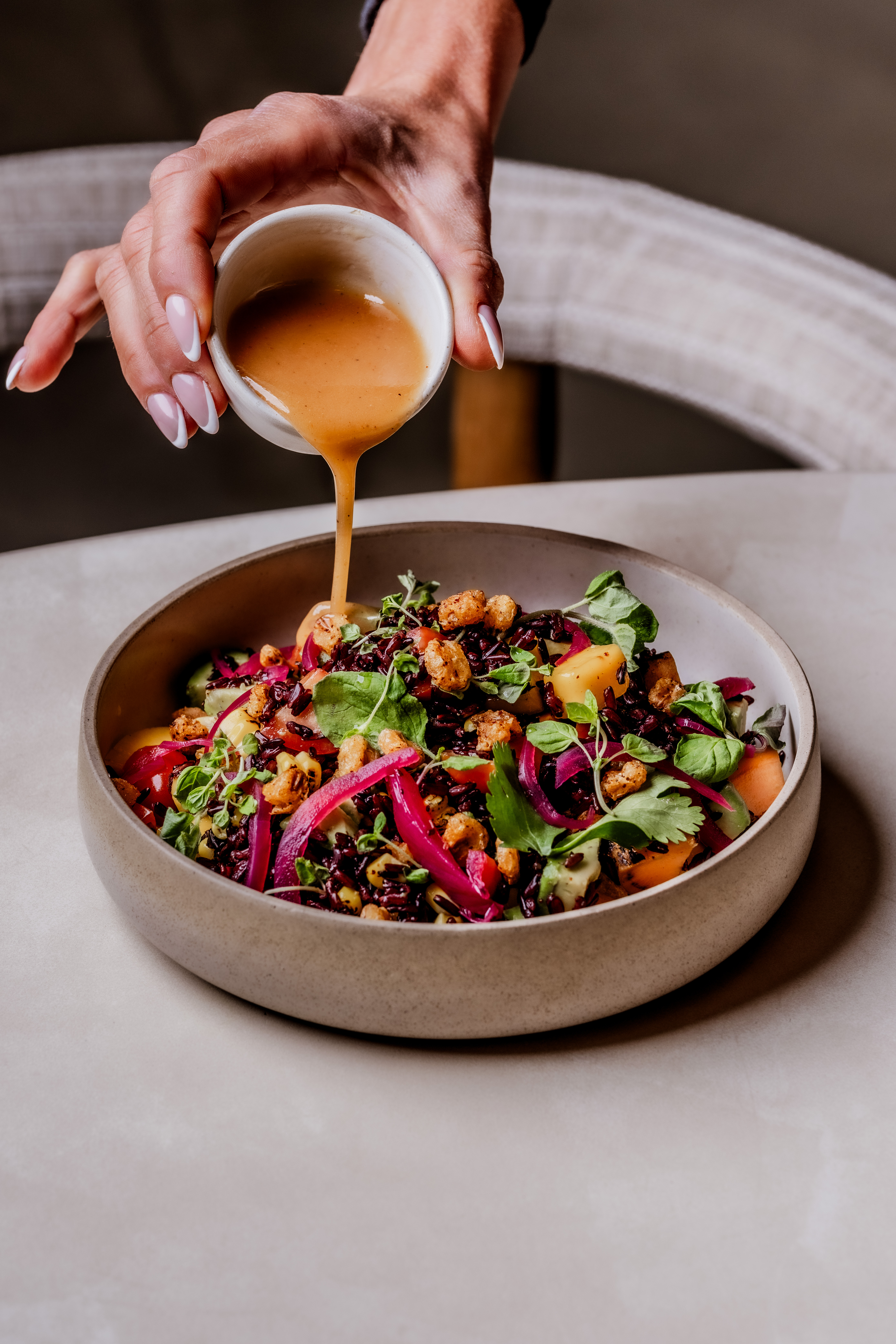 Ixchel Salad Georgia Salamat - a hand pouring dressing over the new wolf moon salad