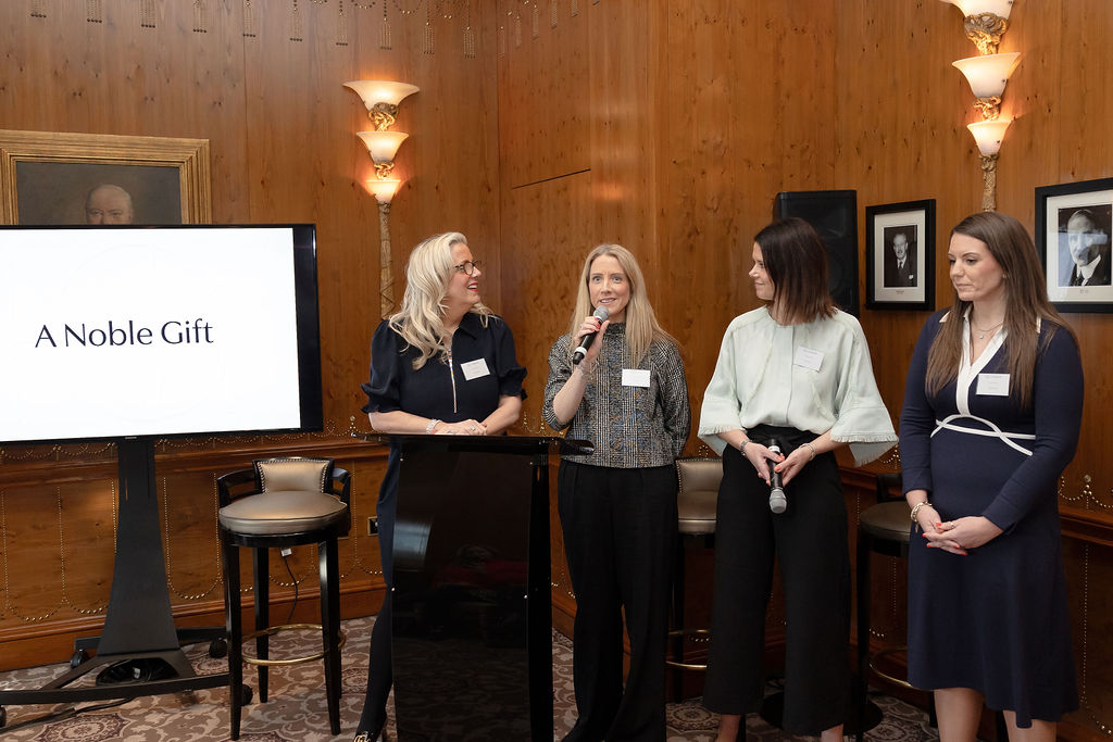 A Noble Gift Charity Auctions - the four co-founders of a noble gift stood alongside a presentation speaking