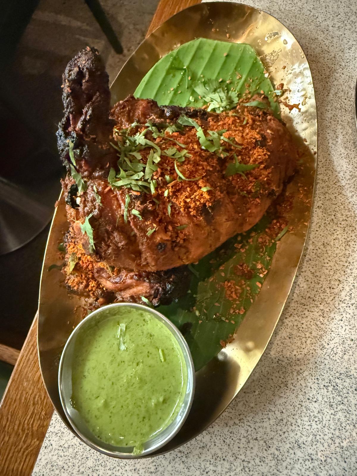 Tamila Restaurant Kings Cross - tandoori chicken on a green leaf and a golden plate alongside a bowl of green sauce