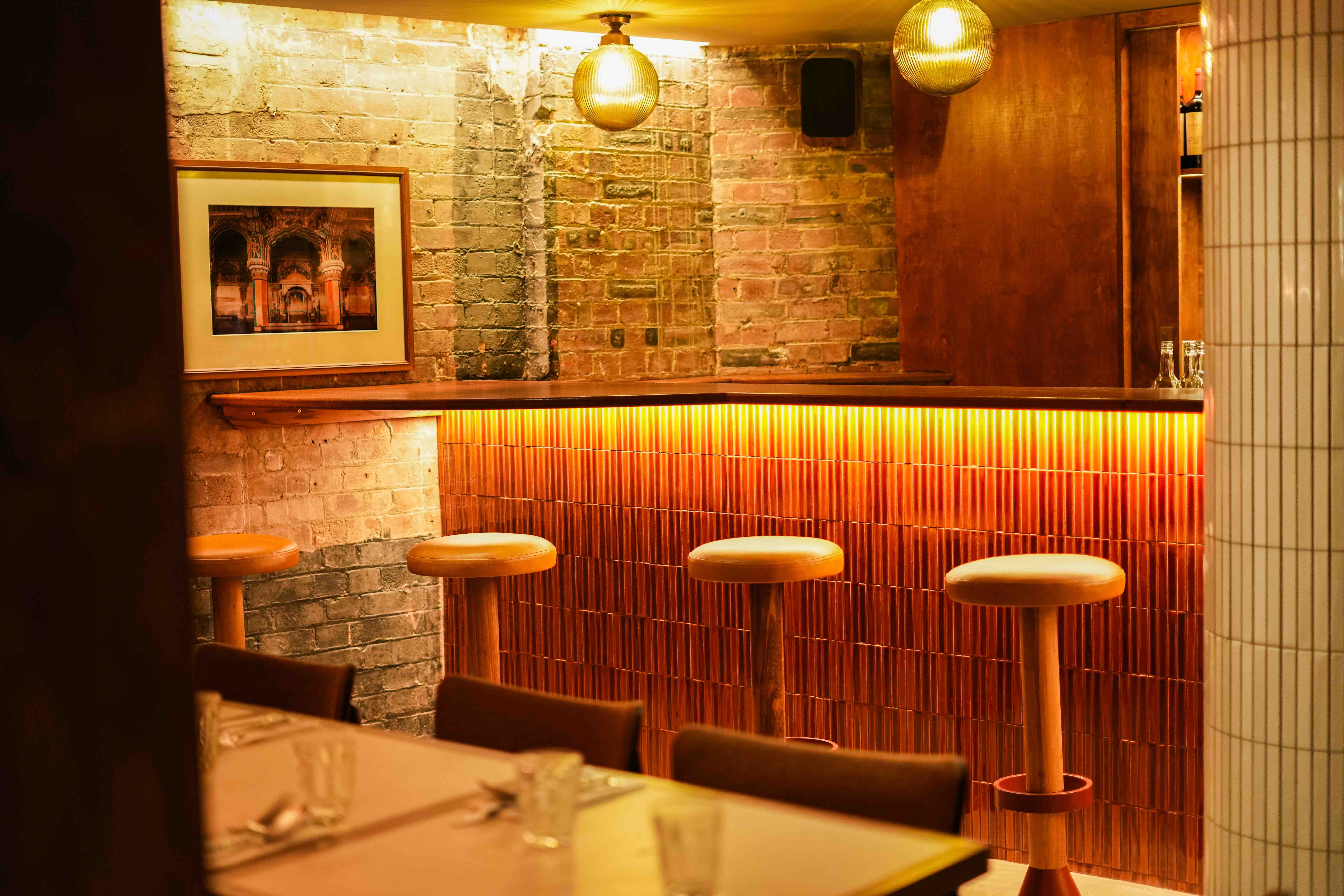 Tamila Restaurant Kings Cross - a bar area with orange tiles, bare-brick walls and a photo of a temple on the wall