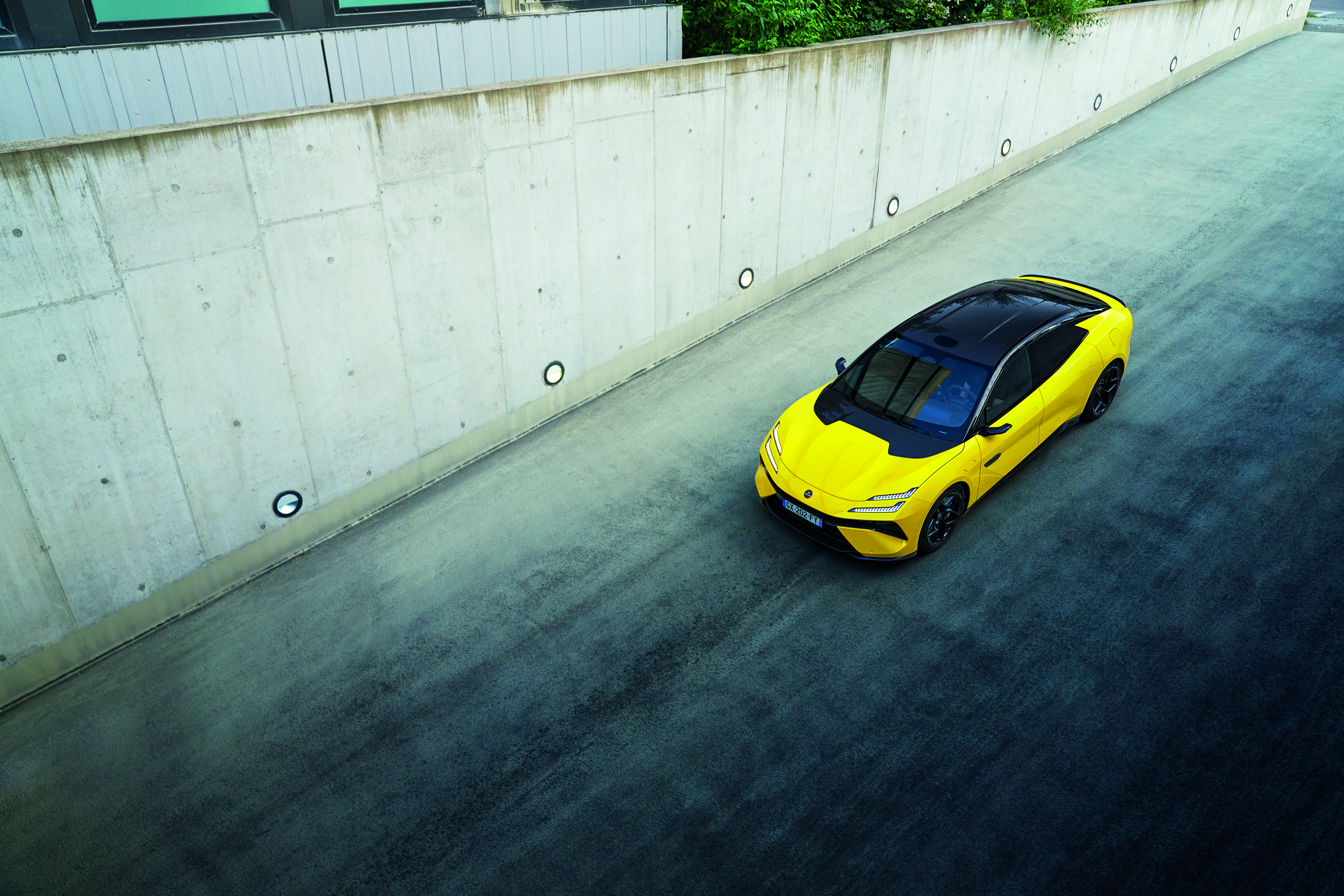 The Lotus Emeya R in neon yellow, driving down a road.