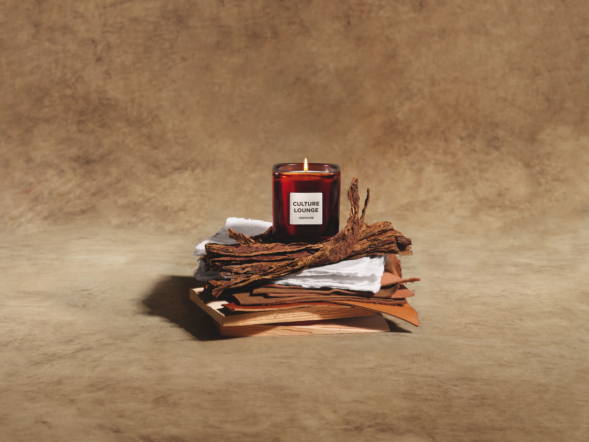 The culture lounge candle photographed on layers of leather and sandalwood as part of The Library by Maison Assouline.