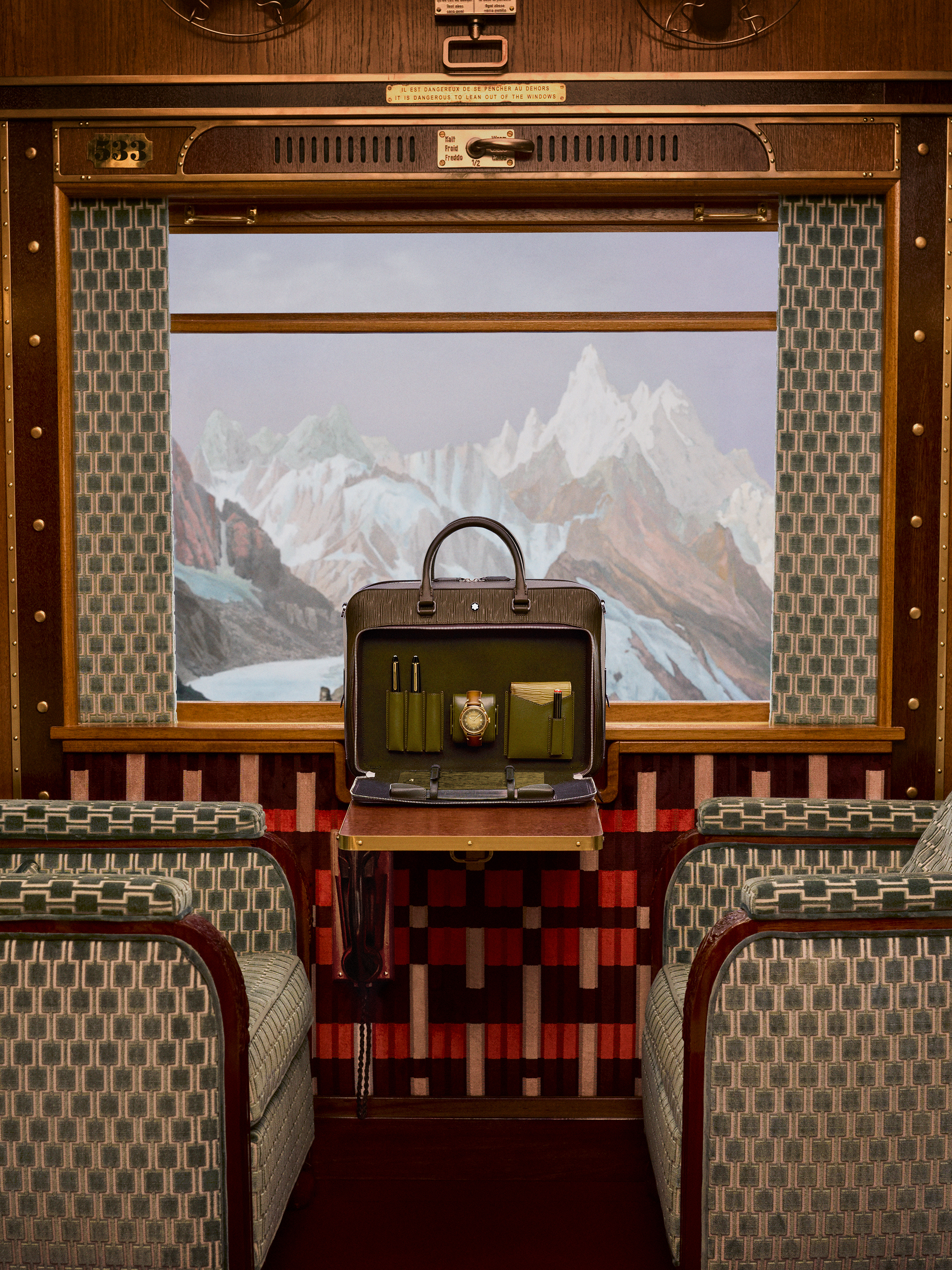 A Montblanc writing bag sits in front of the train carriage's alpine view in a shot accompanying Wes Anderson's promotional film for Montblanc. 