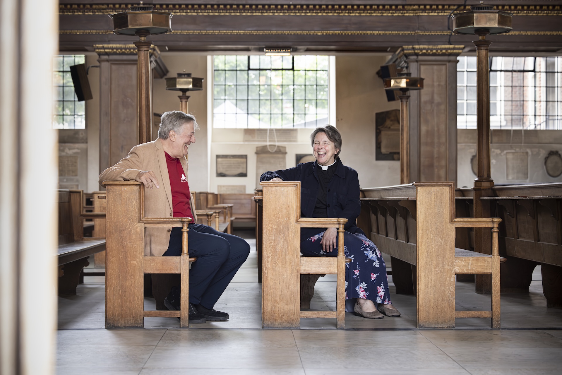 Stephen Fry and Lucy Winkett laughing in the pews of St James's Church Piccadilly.