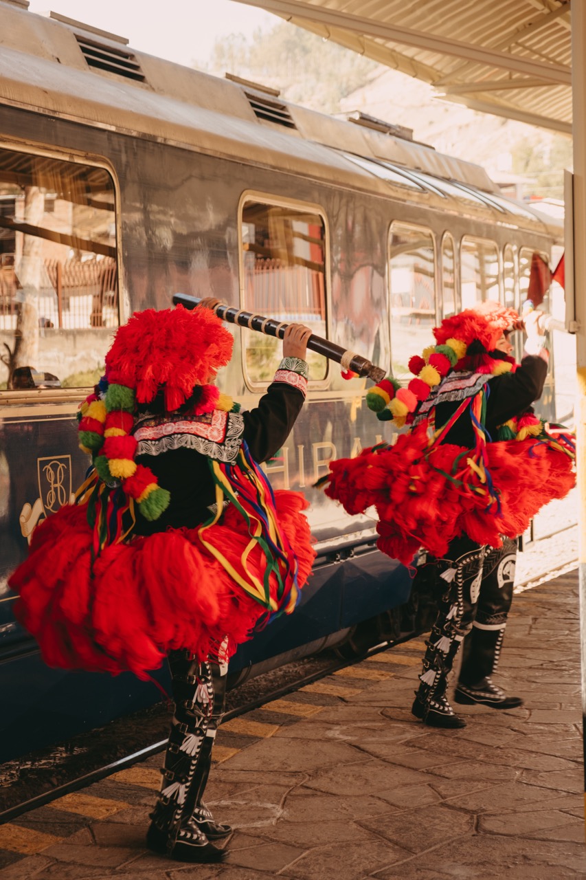 Tradition performers next to the luxury train Machu Picchu.